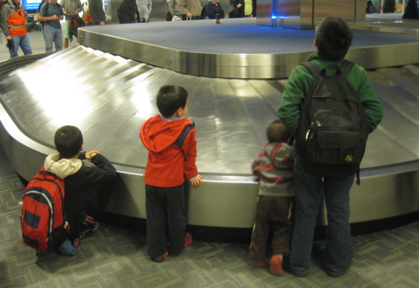 photo of children waiting for their baggage and the luggage carousel